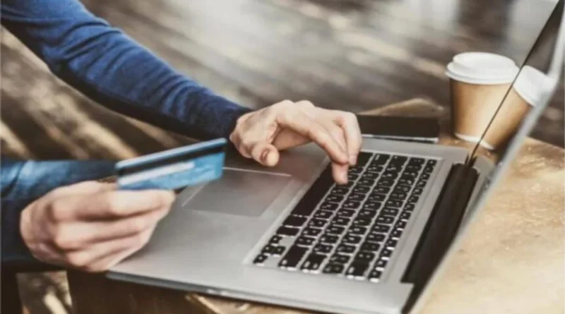 Pessoa utilizando cartão de crédito e laptop para compras online, ilustrando o cenário do Varejo queda janeiro 2026 Índice Stone.